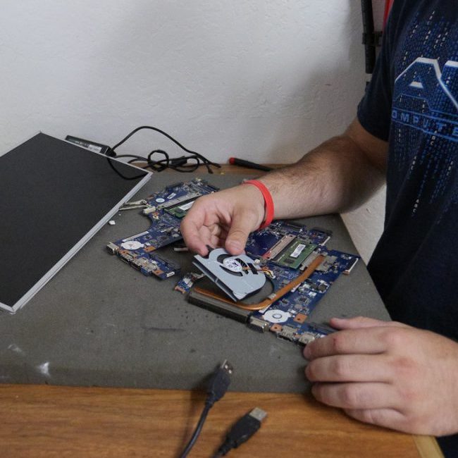 An ABC Computers Plus technician repairs a device